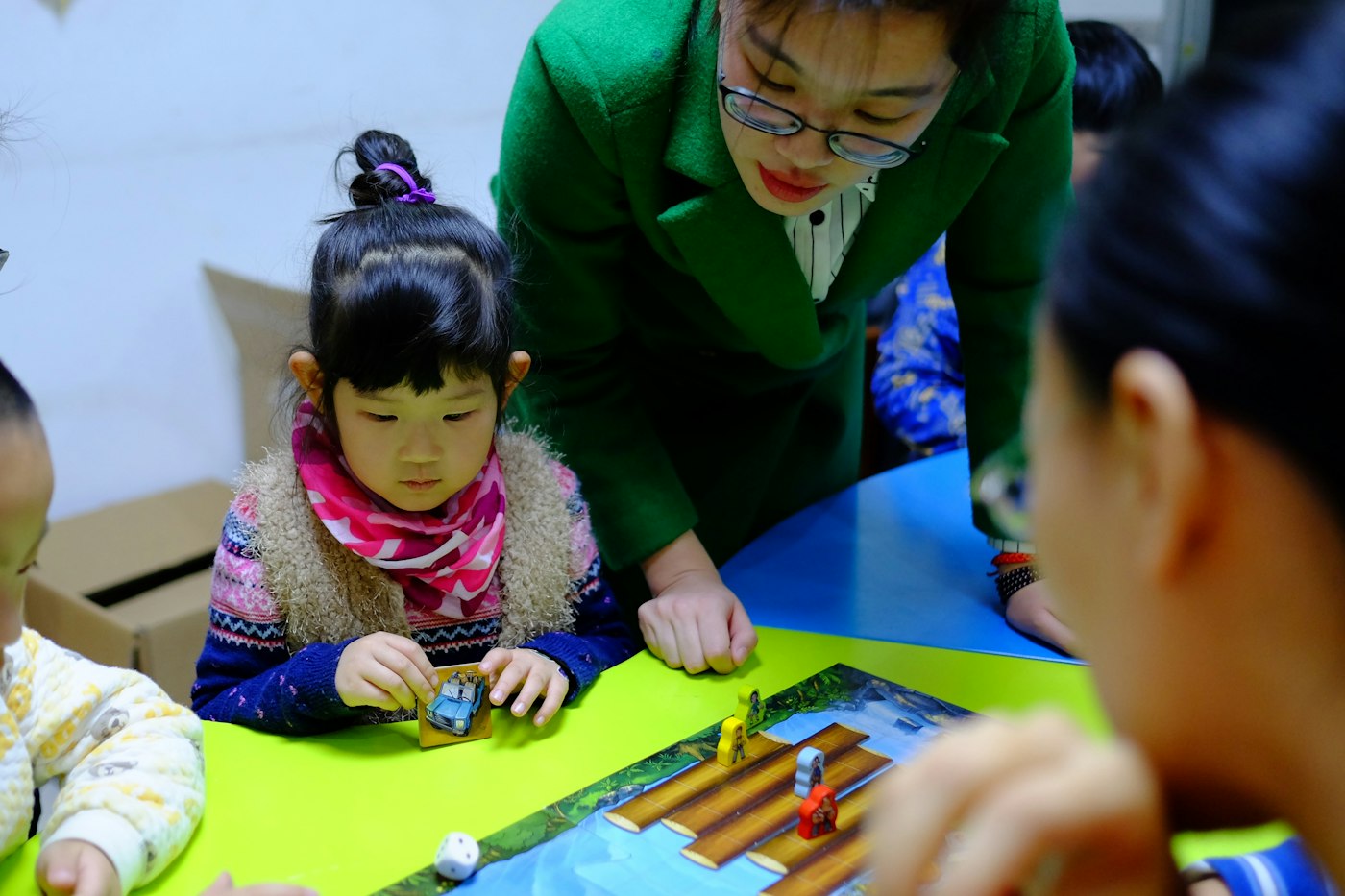 A practitioner leaning over a table where young children are playing a board game