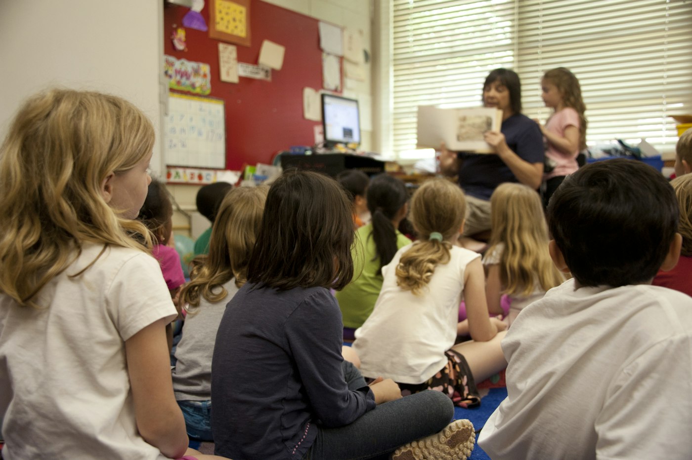 Young children sitting on a classroom floor listening to a story