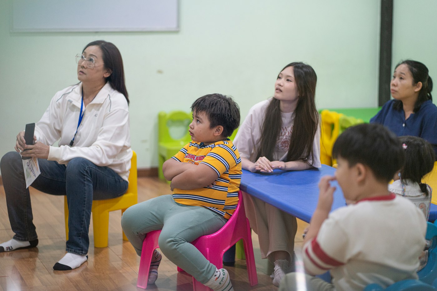 Practitioners sitting with young children at small tables in a nursery room