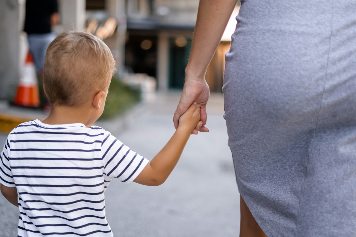 A young boy walking hand in hand with an adult