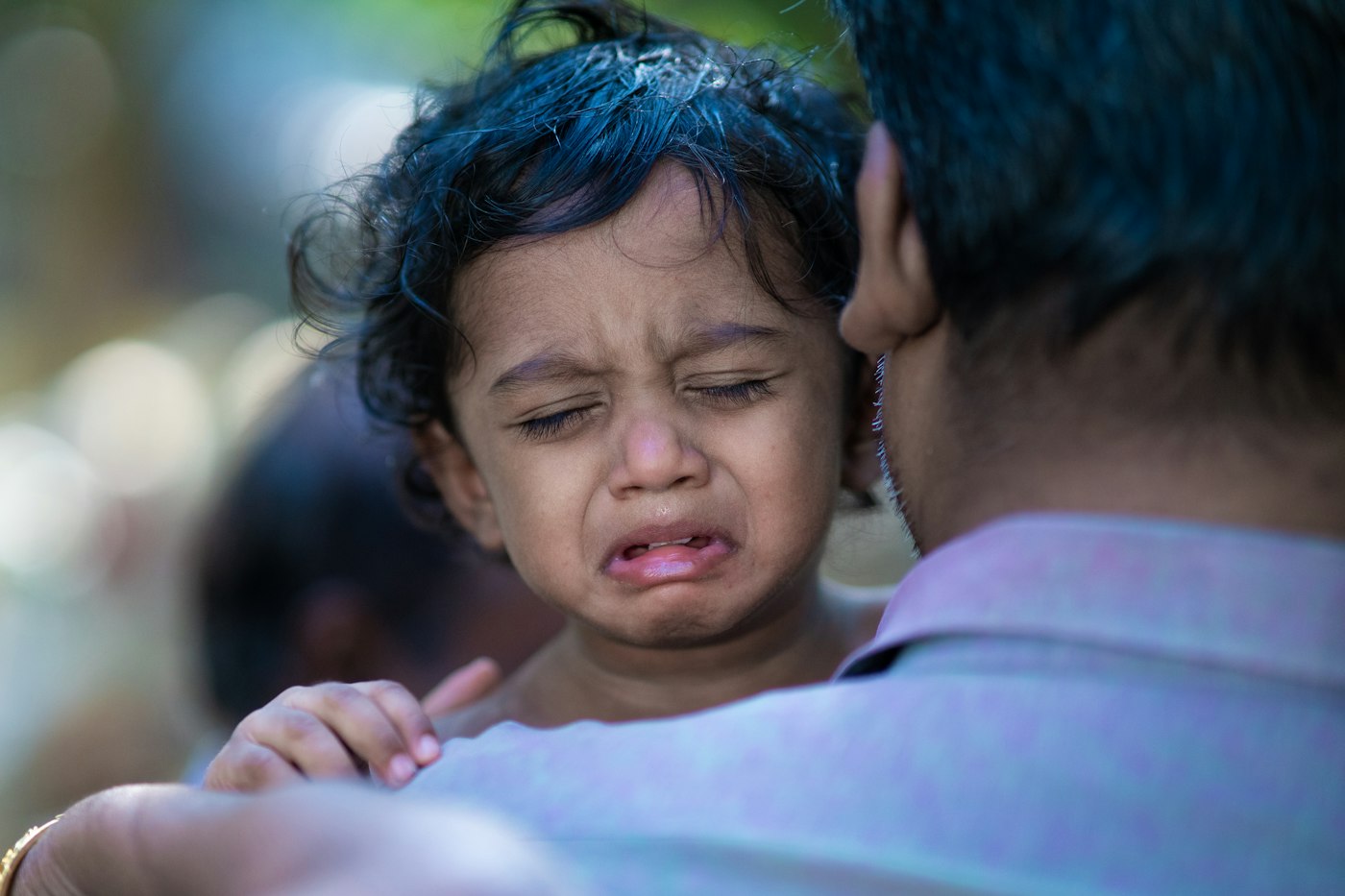 An adult holding a crying toddler close