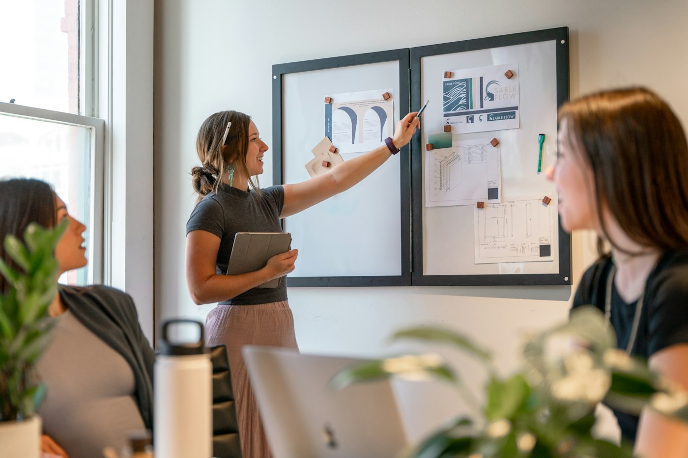 A woman pointing to papers on a board during a team meeting