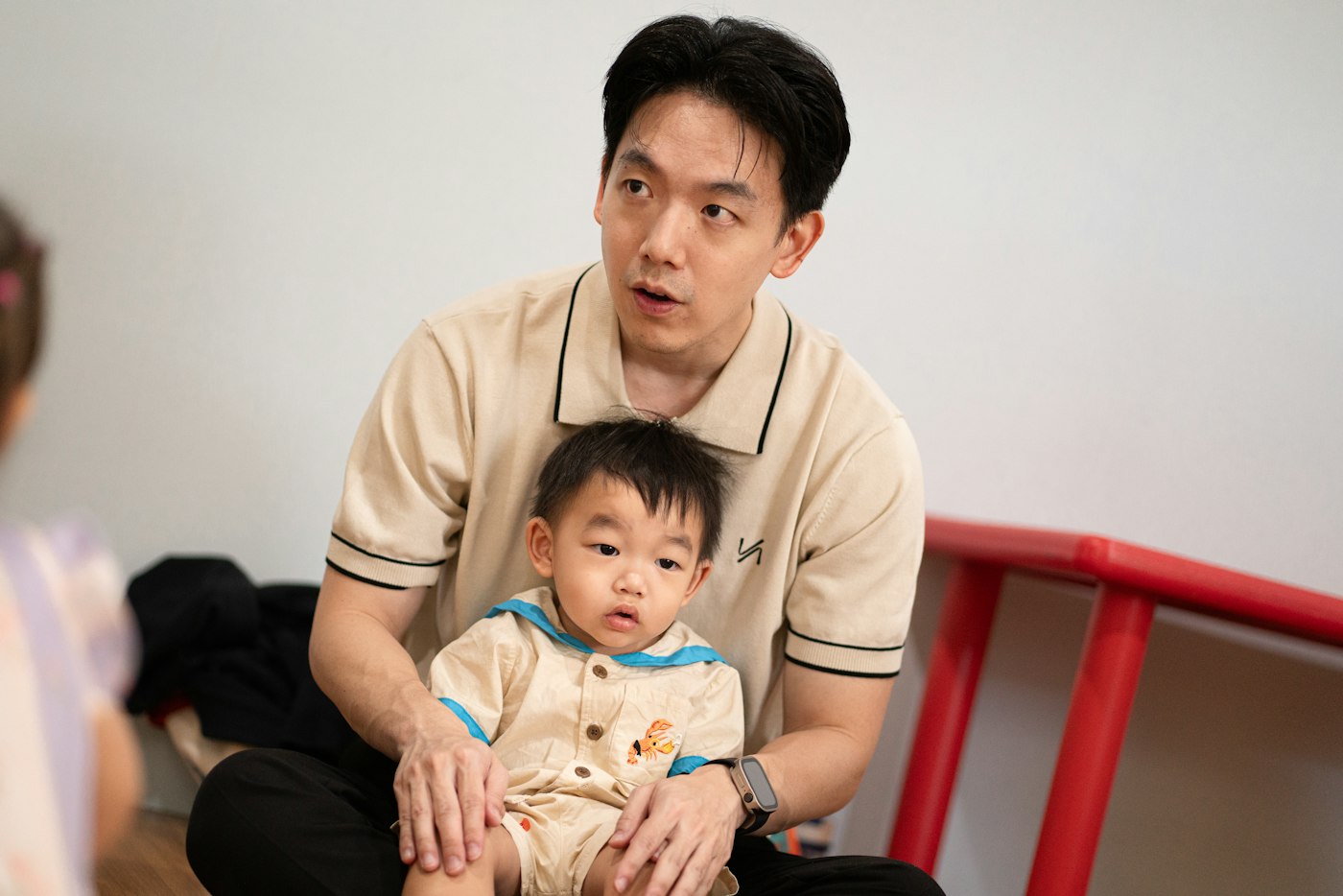 A practitioner sitting with a young child on their lap in a bright nursery room